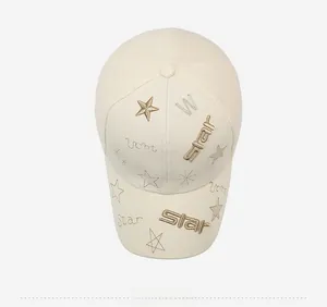 Top view of cream baseball cap featuring golden star embroidery and textile texture