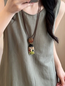 Detail of a vintage ethnic necklace with wood pendant, bronze butterfly and green tassels
