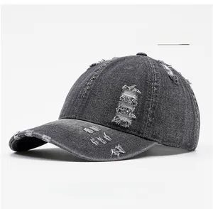 Detail of distressed dark grey washed denim baseball cap showing torn holes and frayed edges