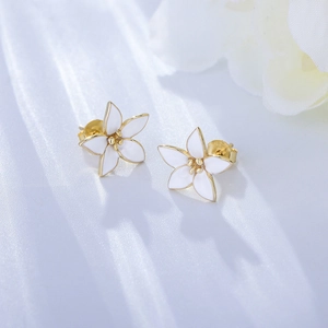 Macro detail of gold-tone flower stud earring showing white enamel and S925 silver stamp