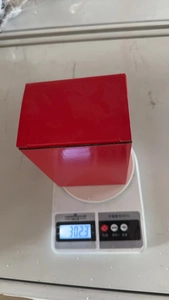 Ceramic Christmas figurine in packaging being weighed at 302.3g on a digital scale