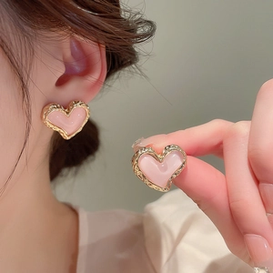 Close-up of pink heart stud earrings with textured gold edges and smooth enamel finish