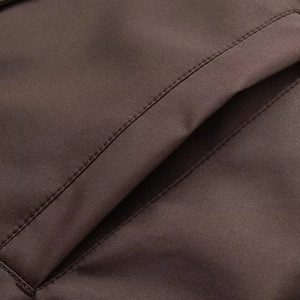 Détail des coutures précises et texture du tissu sur la poche de la parka marron foncé