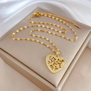 Detail of gold heart pendant with tree of life design and small crystals on flat link chain