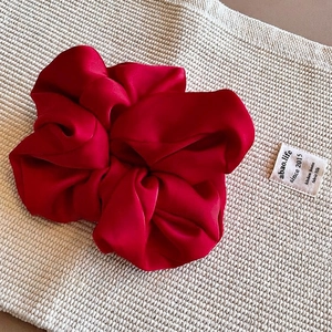 Macro detail of red satin scrunchie showing smooth silk texture on woven fabric