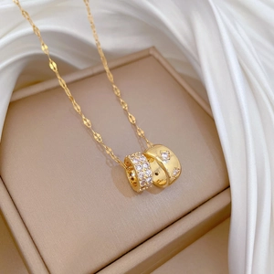 Close-up of golden double-ring necklace with pavé crystals and clover motif on silk
