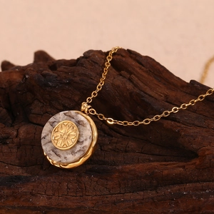 18K gold plated stainless steel necklace with marble sunburst pendant on wood