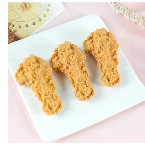 Dettaglio di tre modelli realistici di cosce di pollo fritte in PVC su un piatto bianco