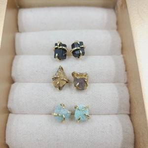 Detailed view of three pairs of natural stone stud earrings in a velvet jewelry box