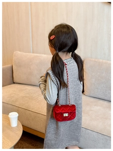 Détail du sac bandoulière en velours rouge avec motif matelassé et fermoir rotatif doré