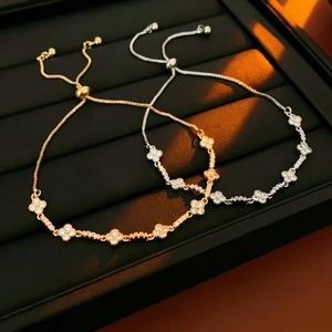 Detailed shot of adjustable clover bracelets in gold and silver with zircon accents