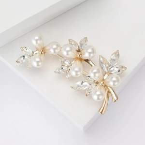 Elegant gold flower brooch with pearls and crystals on a clean geometric background