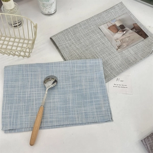 Close-up of minimalist cotton linen placemats with fine woven texture in light blue and grey