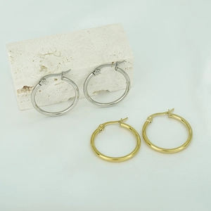 Detailed close-up of minimalist gold and silver hoop earrings with hinged clasps