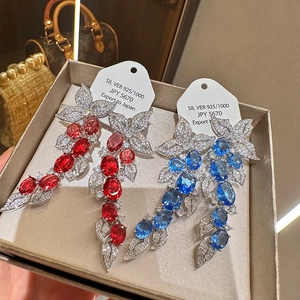 Detail of luxury S925 silver leaf tassel earrings with sparkling red and blue gemstones