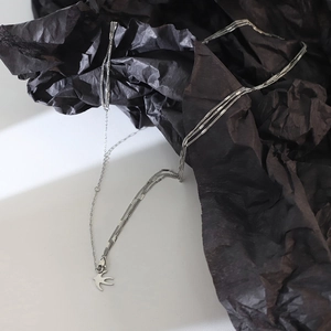 Détail du collier hirondelle argenté multicouche montrant des chaînes texturées élégantes