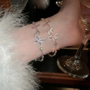 Macro view of butterfly charm bracelet with pink zircon stones and cross star details