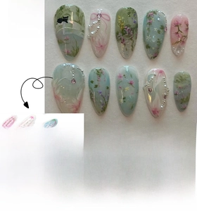 Detail of almond-shaped press-on nails with floral prints, black cats, and 3D pearls