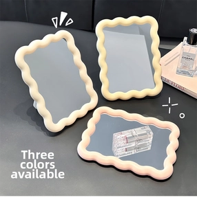 Detail of wavy frame desk makeup mirrors in cream yellow and pink on a stylish vanity