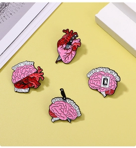 Detail of creative anatomy enamel pins featuring heart and brain designs on yellow background