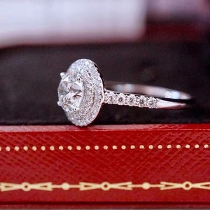 Macro side view of a halo round zircon engagement ring in a classic red jewelry gift box