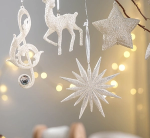 Close-up of white glitter Christmas ornaments with treble clef and deer shapes on a tree