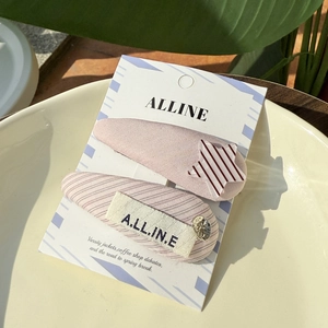 Detailed view of pink fabric hair clips with striped stars and brand woven labels