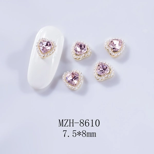 Détail de bijou d'ongle cœur rose 7,5x8mm avec perles et base dorée sur un ongle
