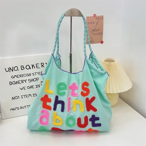 Detailed close-up of colorful towel embroidery and woven handle on the canvas tote bag
