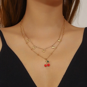 Double-layered gold necklace with sweet red and green cherry pendants worn by model