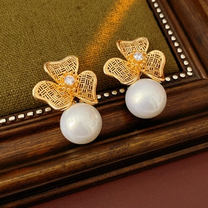 Detail of vintage gold flower earrings with central zircon and white pearl on wood