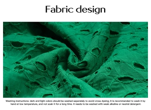 Macro shot of green hollow-out embroidery fabric with detailed washing instructions
