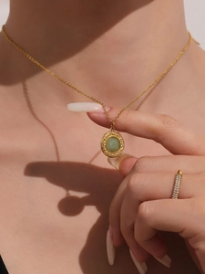 Macro shot of gold necklace with green turquoise pendant and diamond ring set