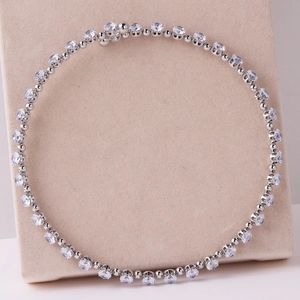 Elegant silver tennis necklace with heart and drop zirconia stones on a beige stand