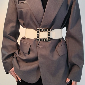 Detail of white leather waist belt featuring a large square buckle with black crystals
