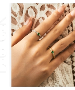 Detail of green heart gemstone ring in gold and silver finish on lace background