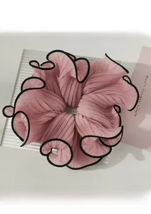 Detail of light pink chiffon scrunchie with elegant black piping and pleated texture