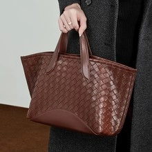 Detailed macro view of dark brown woven leather tote bag with classic weave texture