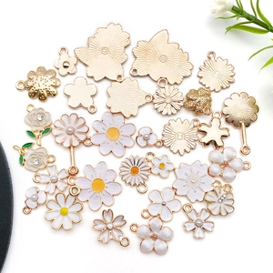 Detailed overhead shot of white daisy and cherry blossom DIY enamel charms with gold edges