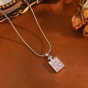 Detailed close-up of a silver perfume bottle pendant with pink cubic zirconia on a snake chain