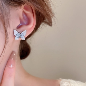Close-up of butterfly earrings with silver frame and gradient crystal finish on ears