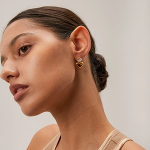 Close-up of model wearing gold heart earrings with sparkling crystals for women