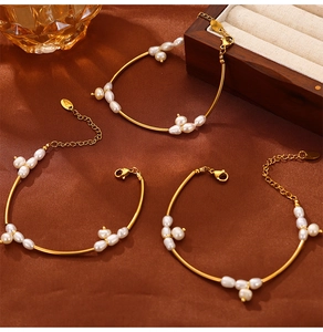 Detailed view of elegant gold-tone bangles with baroque pearls on brown silk background