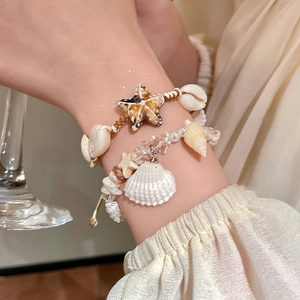 Detail showing shell, conch, and starfish pendants on a layered seaside holiday bracelet