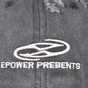 Close-up of intricate white embroidery and distressed washed cotton fabric on baseball cap