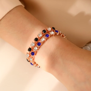 Bracelet double rang en or rose avec cristaux bleus et blancs porté au poignet