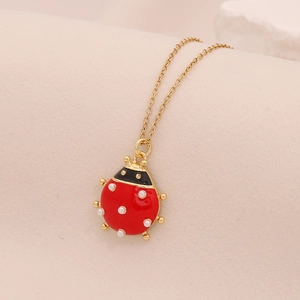 Dettaglio del ciondolo a coccinella in smalto rosso su una catena dorata