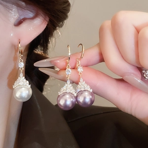 Détail de boucles d'oreilles en perles dorées en forme de goutte et zircons brillants