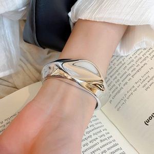 Macro detail of a wide silver liquid metal cuff bracelet with a high-polished mirror finish