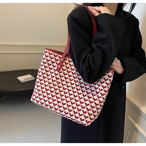 Red houndstooth tote bag with heart pattern shown being held by a model in black